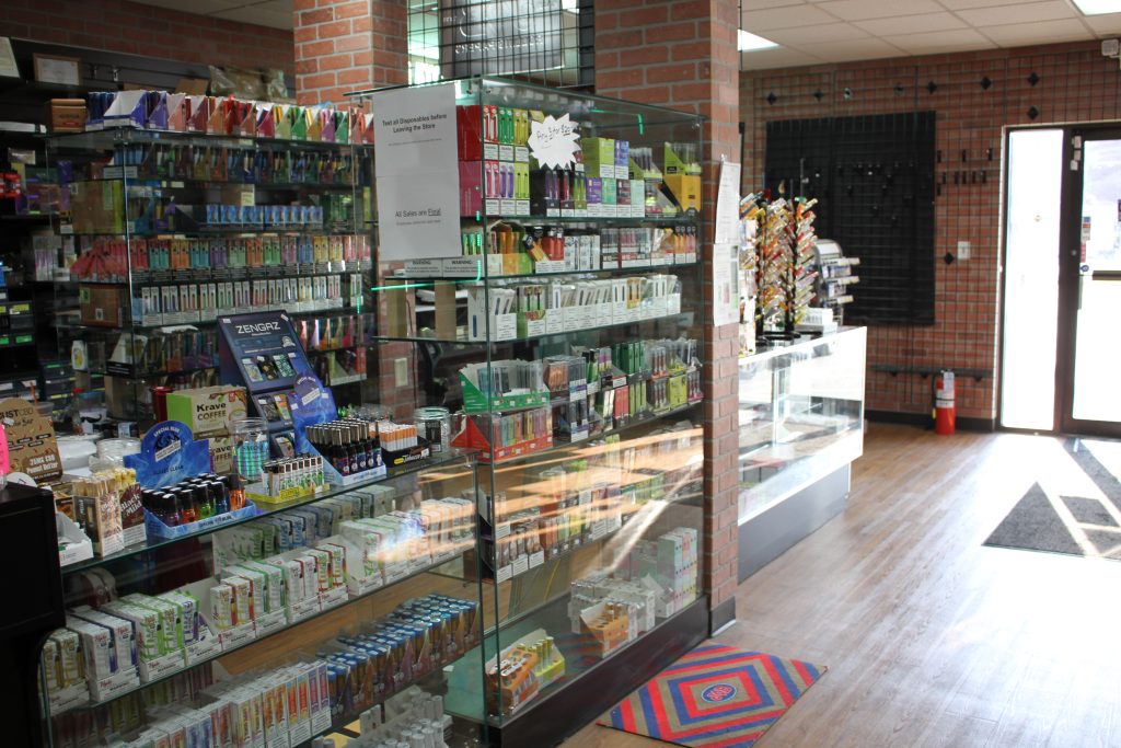 Glass display case with disposable vapes, e-liquid pods, and vape accessories inside a modern vape shop